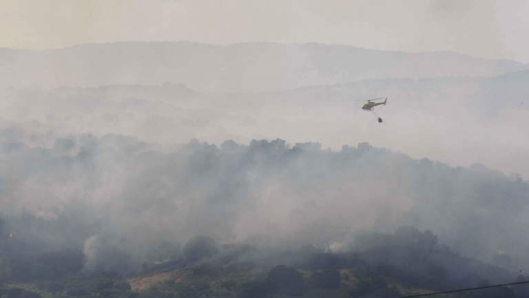 UN HELICÓPTERO TRABAJA EN LA ZONA CASTIGADA POR EL INCENDIO.